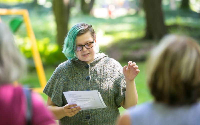 Woman with green hair reading to an audience