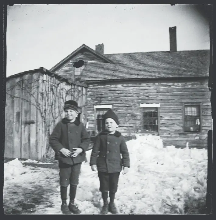 2 children outside of house in winter ca. 1890-1915.